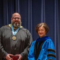 Provost Mili takes picture on stage with man